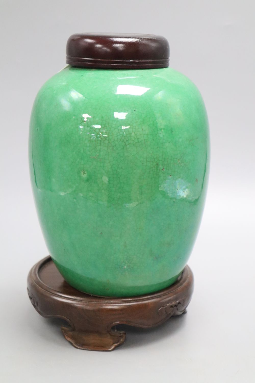 A 19th century Chinese green crackle glaze jar, drilled, wood cover and stand, overall height 25cm